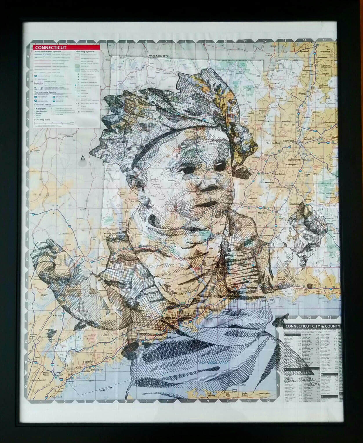 Lisa Hunter's pen and ink illustration of a baby wearing a crown of collaged leaves made of travel map pieces and a bandana all drawn over a travel map framed in black. Feather Road Design Studio, LLC