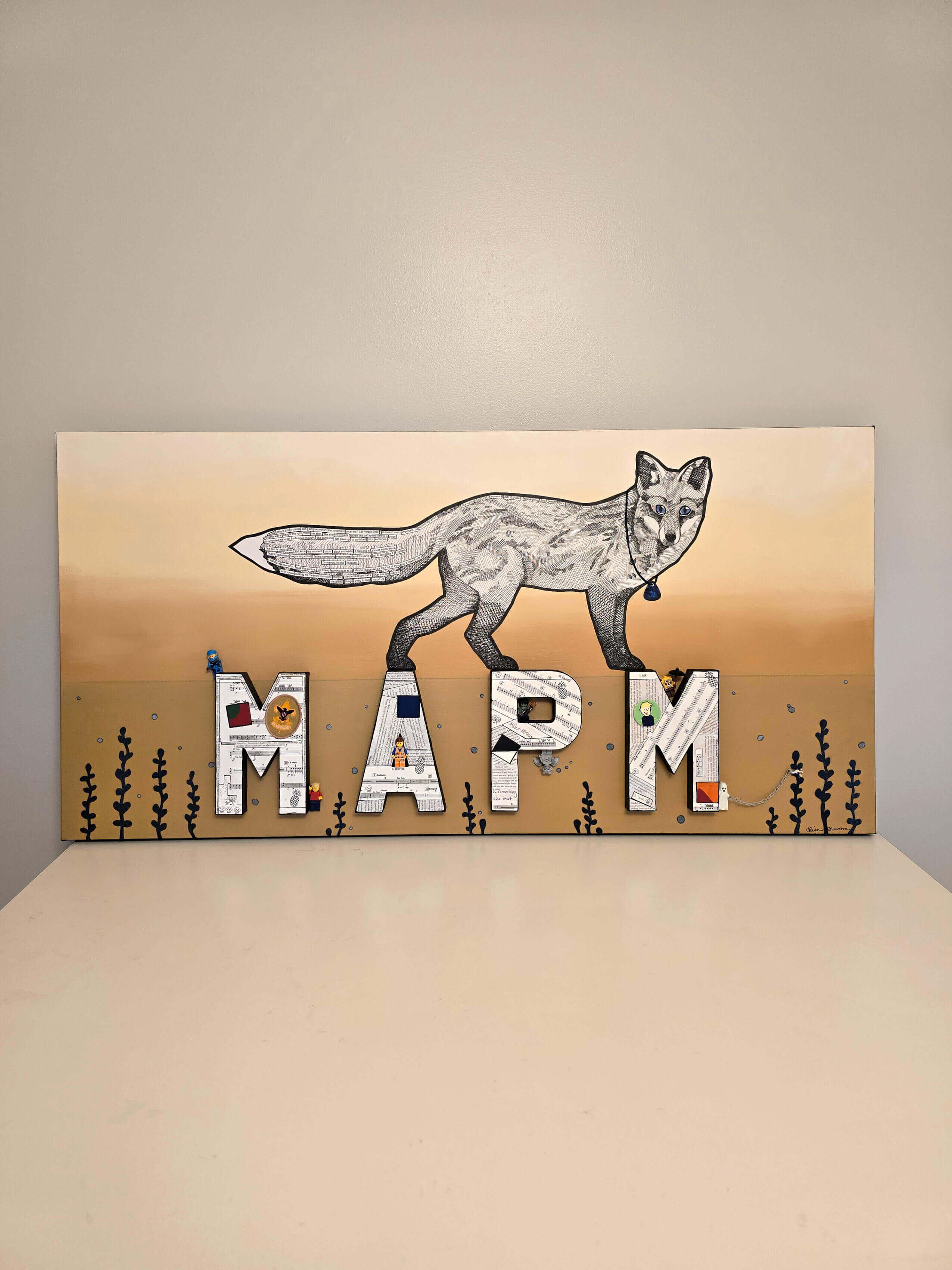 Lisa Hunter's horizontal rectangular artwork w/burnt sienna gradient background consisting of black/white illustrated fox w/bushy tail wearing blue guitar pick around neck. Fox is walking across letters under water. Feather Road Design Studio, LLC